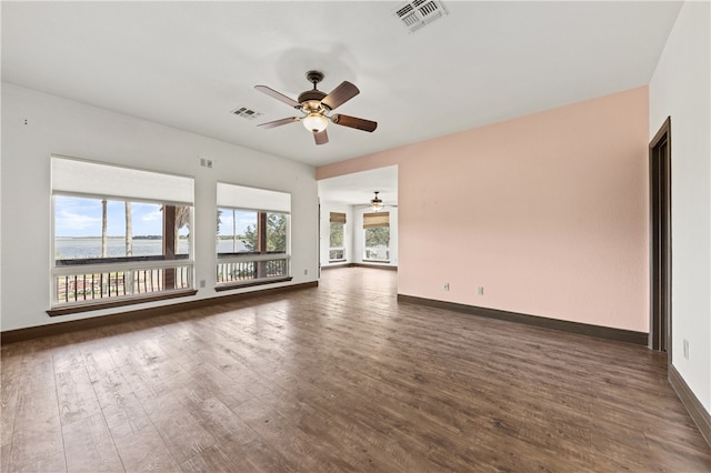 empty room featuring dark hardwood / wood-style flooring, a wealth of natural light, and ceiling fan