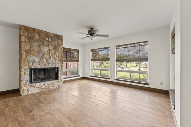 unfurnished living room featuring a stone fireplace, wood-type flooring, and ceiling fan