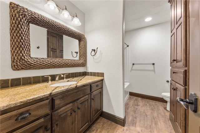 bathroom featuring toilet, vanity, wood-type flooring, and walk in shower