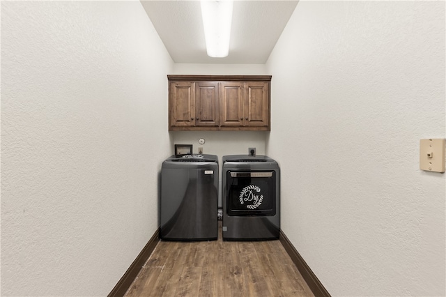 laundry room featuring cabinets, washer and dryer, and dark hardwood / wood-style flooring