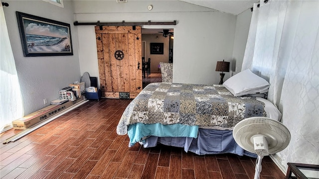 bedroom with a barn door and dark hardwood / wood-style floors