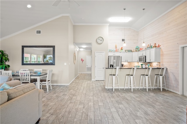 kitchen featuring white cabinets, kitchen peninsula, a breakfast bar area, crown molding, and appliances with stainless steel finishes