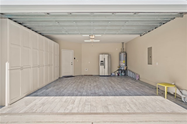 garage featuring electric panel, stainless steel fridge with ice dispenser, and water heater