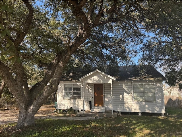 bungalow-style house featuring entry steps, fence, and a front lawn