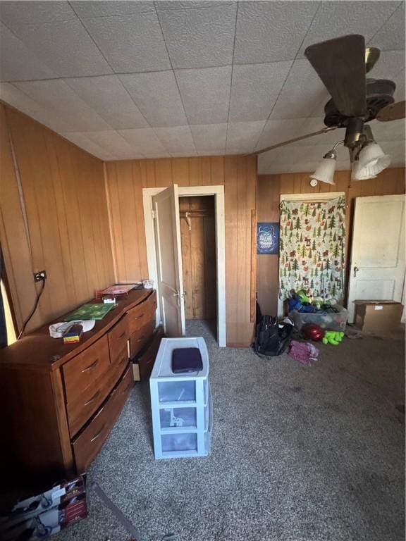 miscellaneous room with carpet floors, ceiling fan, and wooden walls