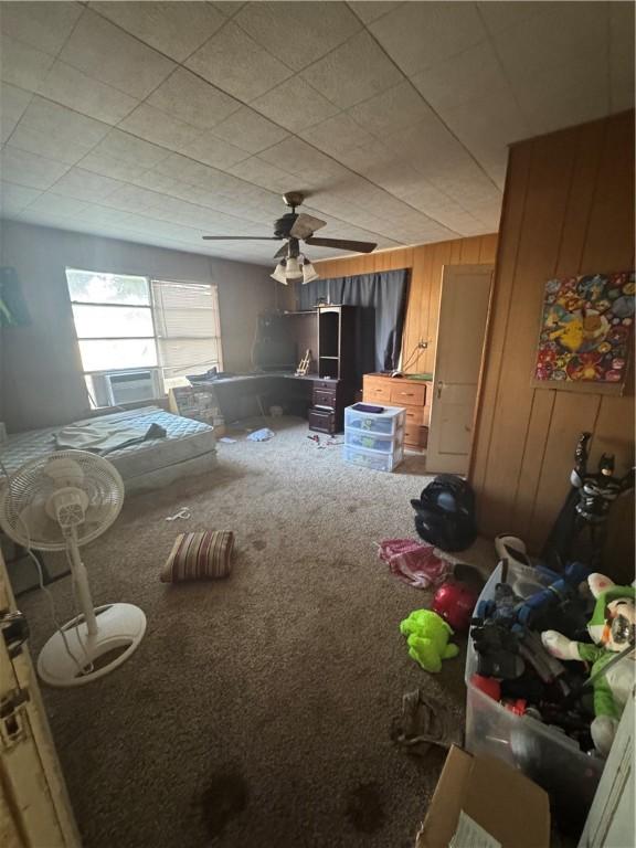 carpeted bedroom with wooden walls and a ceiling fan