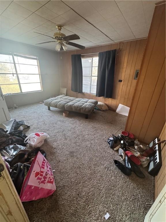 carpeted bedroom with wooden walls and a ceiling fan