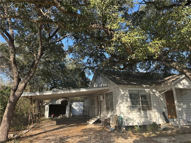 view of side of property featuring entry steps, driveway, and an attached carport