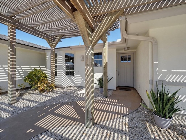 property entrance with stucco siding and a pergola