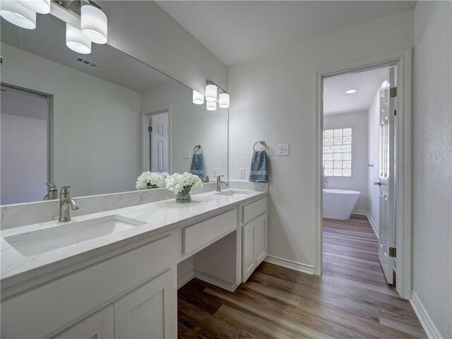 13818 Halyard Dr, Corpus Christi, TX 78418 - bathroom with double vanity, wood finished floors, a soaking tub, and a sink