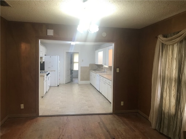 kitchen featuring light hardwood / wood-style floors, white appliances, white cabinetry, and a textured ceiling