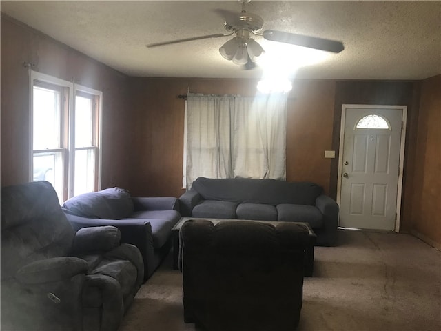 living room featuring carpet flooring, ceiling fan, and a textured ceiling