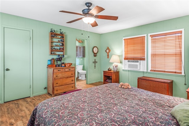 bedroom featuring connected bathroom, light hardwood / wood-style floors, ceiling fan, and cooling unit