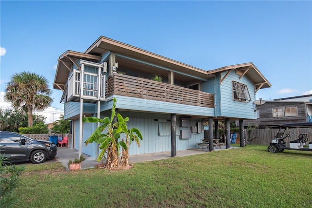 back of house with a garage, a lawn, and a balcony