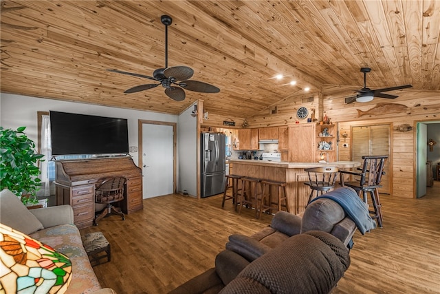 living room with wood walls, light hardwood / wood-style floors, and lofted ceiling