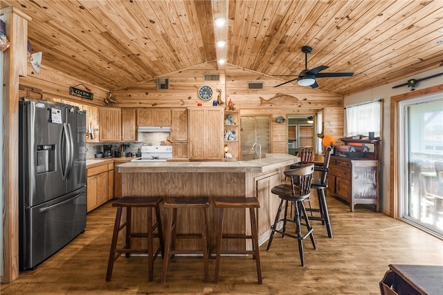 kitchen featuring hardwood / wood-style floors, white range, lofted ceiling, and stainless steel fridge