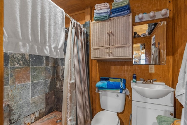 bathroom featuring toilet, vanity, wooden walls, and curtained shower