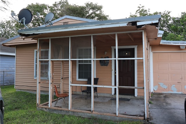 rear view of property with a garage and a sunroom