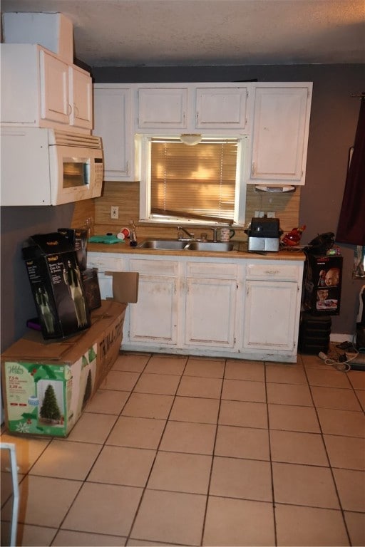 kitchen featuring white cabinets, sink, tasteful backsplash, and light tile patterned flooring