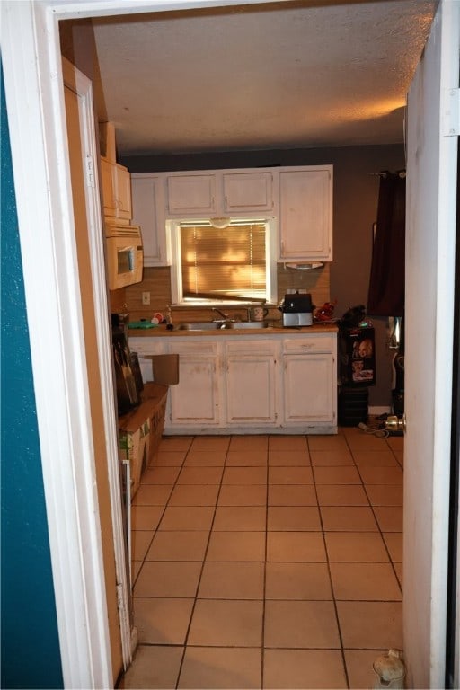 kitchen with white cabinetry, light tile patterned flooring, and tasteful backsplash