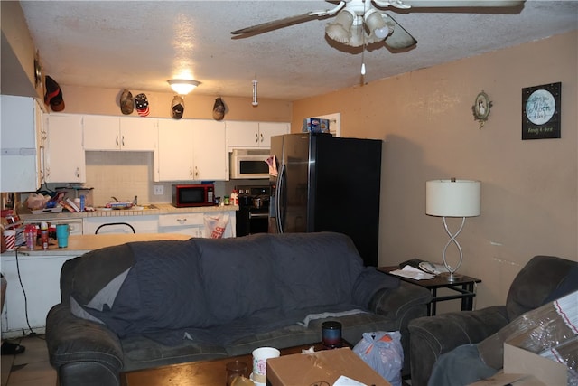 living room with a textured ceiling, ceiling fan, and sink