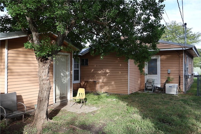 rear view of house featuring cooling unit and a lawn