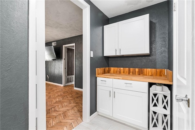 5110 Cascade Dr, Corpus Christi, TX 78413 - kitchen with butcher block counters, white cabinetry, and a textured wall
