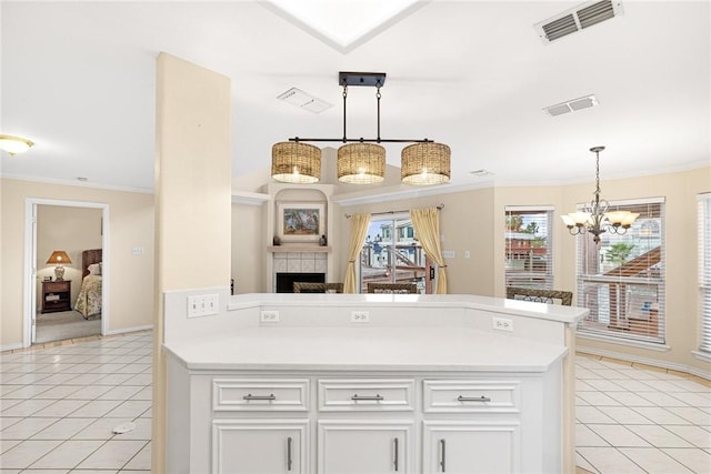 kitchen featuring a tile fireplace, decorative light fixtures, white cabinets, and light tile patterned flooring