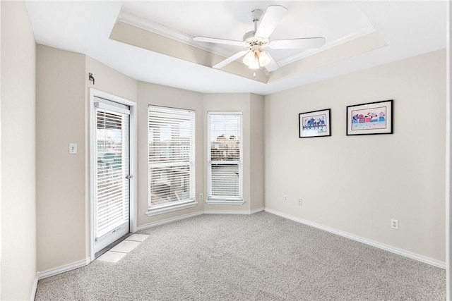 carpeted spare room with a raised ceiling and ceiling fan