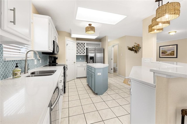 kitchen featuring appliances with stainless steel finishes, sink, decorative light fixtures, a center island, and white cabinetry