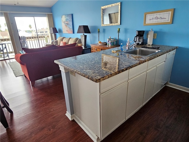 kitchen with sink, white dishwasher, dark stone counters, dark hardwood / wood-style floors, and white cabinets