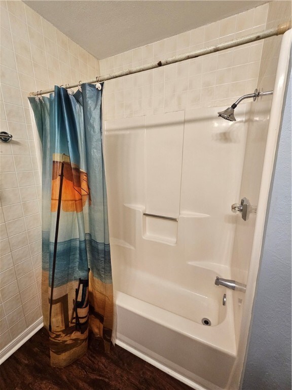 bathroom with shower / bath combo with shower curtain and wood-type flooring