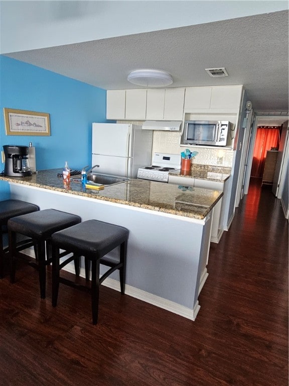 kitchen featuring white appliances, white cabinetry, and kitchen peninsula