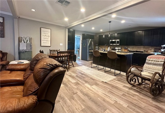 living room featuring crown molding, sink, and light wood-type flooring