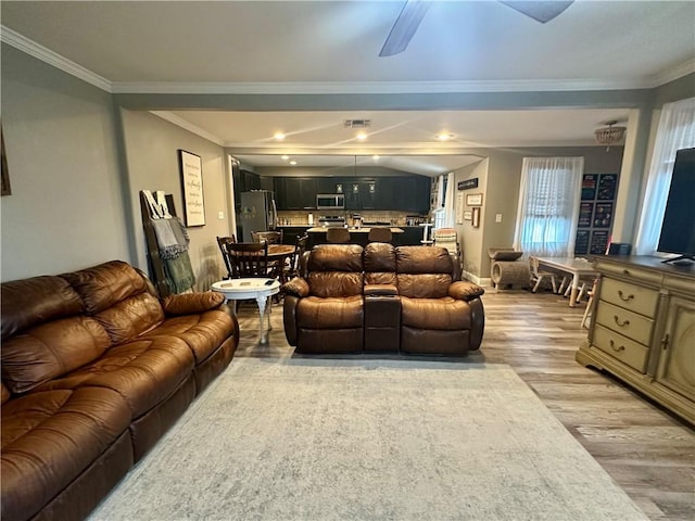 living room with ornamental molding, vaulted ceiling, and light wood-type flooring