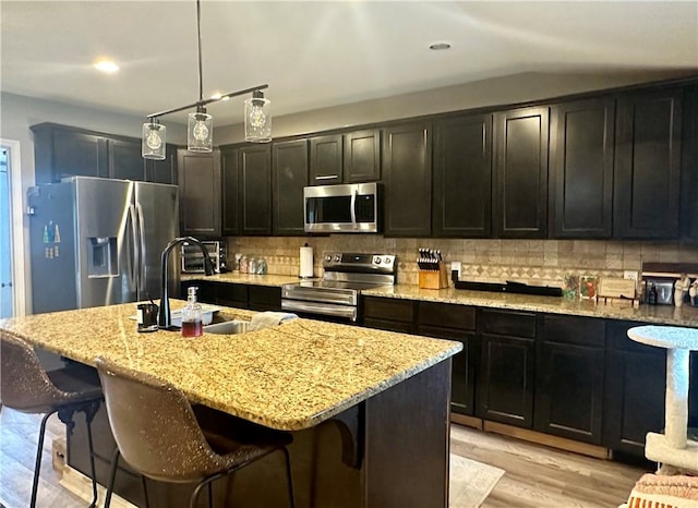 kitchen with appliances with stainless steel finishes, sink, an island with sink, and a breakfast bar area