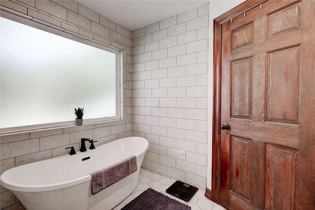 bathroom with tile patterned floors, a tub to relax in, and tile walls