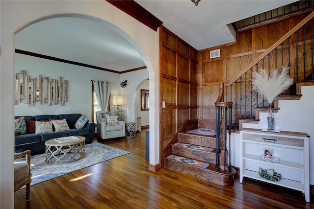 living room featuring ornamental molding, arched walkways, stairs, and wood finished floors