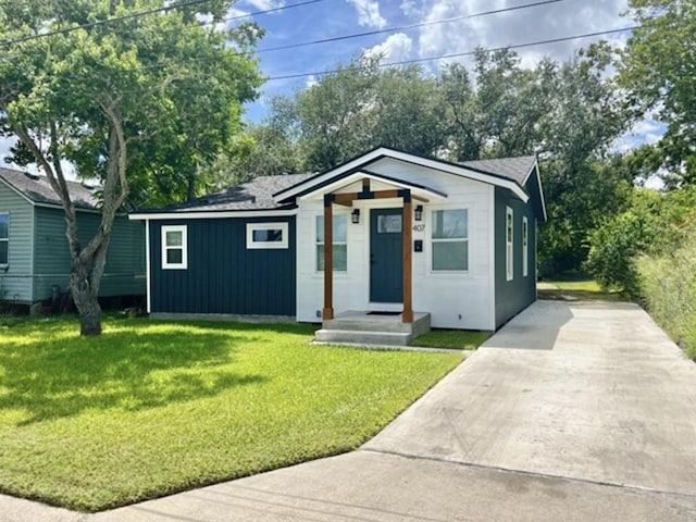 bungalow-style house with concrete driveway, a front lawn, and board and batten siding