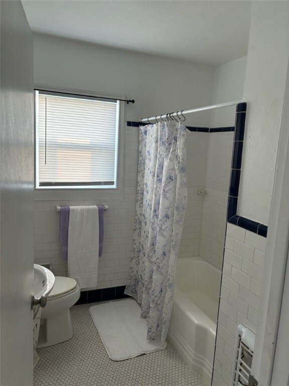 bathroom with toilet, radiator heating unit, tile patterned floors, and shower / tub combo