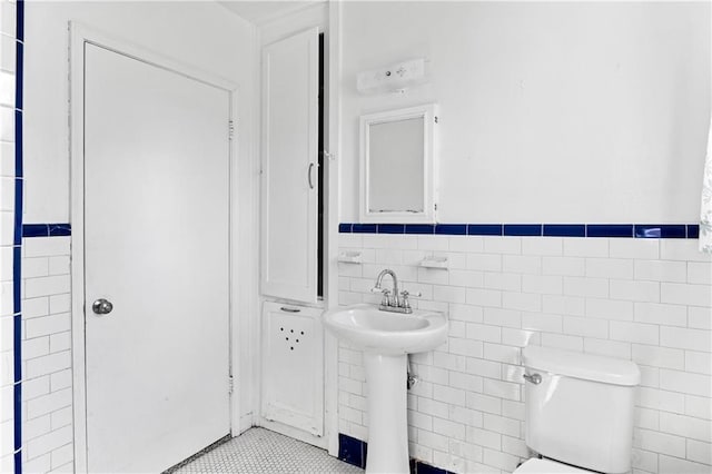 bathroom featuring sink, tile patterned flooring, toilet, and tile walls