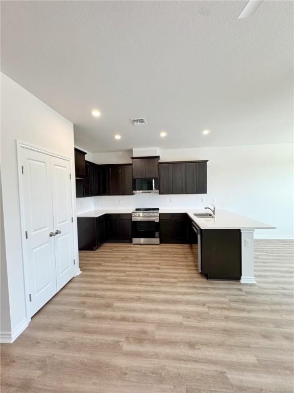 1931 Topwater, Aransas Pass, TX 78336 - kitchen with appliances with stainless steel finishes, a sink, light wood-style floors, light countertops, and a peninsula
