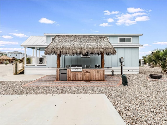 rear view of property with board and batten siding and an outdoor kitchen