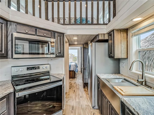 kitchen featuring light wood-type flooring, dark brown cabinets, stainless steel appliances, and a sink