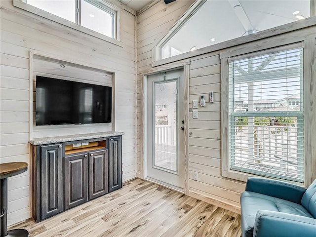 living area featuring light wood-style flooring and wooden walls