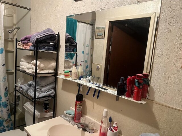 bathroom with curtained shower, sink, and toilet