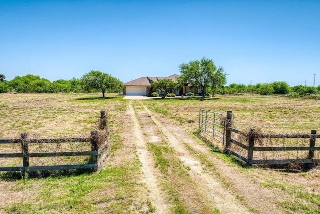 view of street featuring a gated entry, driveway, and a rural view