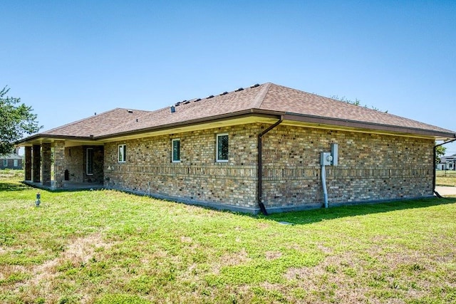 rear view of property featuring a yard and brick siding