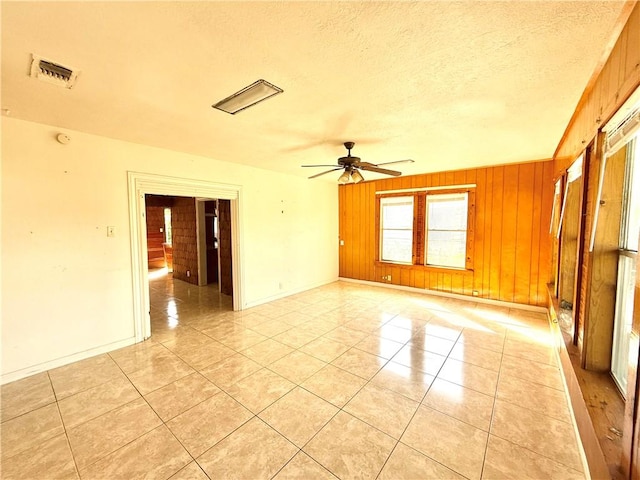 1609 15th St, Corpus Christi, TX 78404 - unfurnished room featuring ceiling fan, light tile patterned flooring, wooden walls, and a textured ceiling