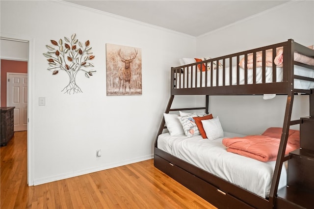 bedroom with baseboards, ornamental molding, and wood finished floors